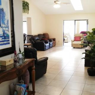 A spacious and bright living room featuring comfortable seating, plants, and artwork.