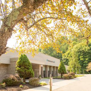 A serene view of a modern building surrounded by autumn foliage.