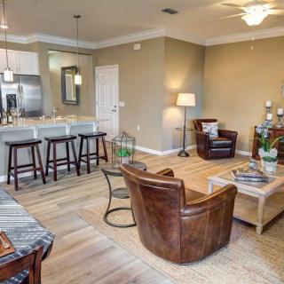 A modern open-concept living room with a connected kitchen, featuring stylish furniture and hardwood floors.
