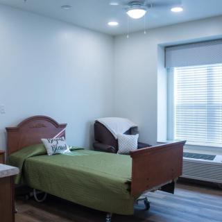A clean and well-lit hospital room with a single bed and a window.