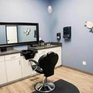 A modern hair salon station with a barber chair and mirror.