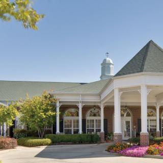 A large building with an elegant entrance, featuring columns and a landscaped front area.