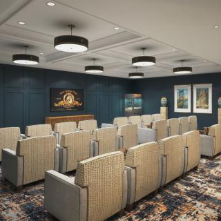 A modern conference room with rows of seating, a large screen at the front, and stylish lighting fixtures.