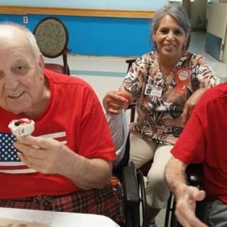 Elderly individuals enjoying a celebration with cupcakes and smiles.