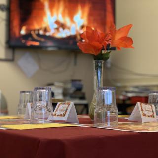 A cozy dining table setup with a warm fireplace in the background.