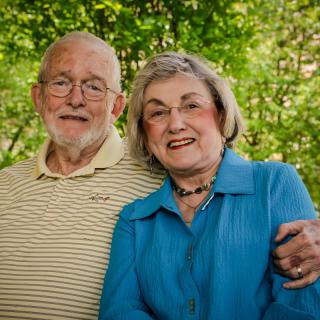 An elderly couple smiling and enjoying time together outdoors.