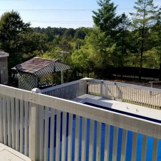 A serene backyard featuring a fenced pool and gazebo with lush greenery in the background.