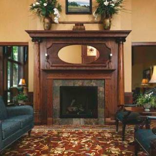 A cozy living room featuring a wooden fireplace mantle, elegant floral decor, and inviting seating.