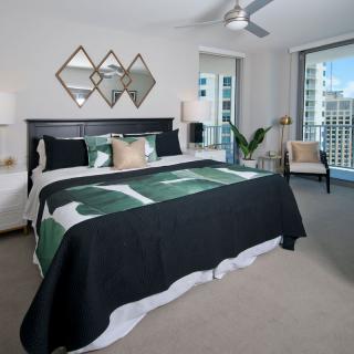 A modern bedroom with a king-size bed, stylish decor, and a view of the cityscape through large windows.