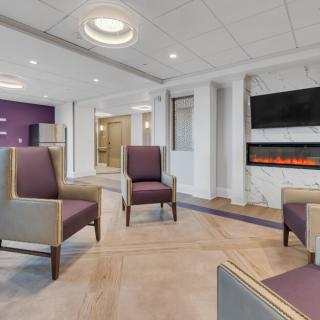 A modern lobby with comfortable seating, a television, and a fireplace.