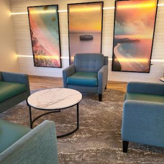 A cozy lounge area featuring teal chairs, a marble table, and vibrant artwork.