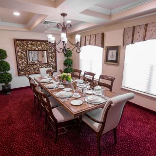 An elegant dining room with a formal table setting and chandelier.