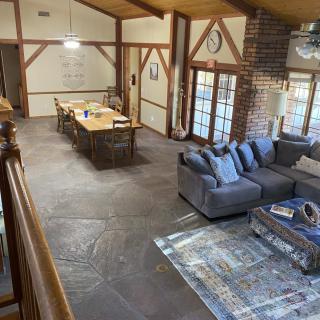 A spacious living area with rustic decor, featuring a comfortable sofa, dining table, and exposed wooden beams.