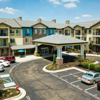 A modern apartment complex with a landscaped entrance and parking lot.