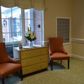 A cozy corner with two chairs and a dresser near a window.