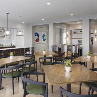 A modern cafe interior with neatly arranged tables and chairs, stylish lighting, and minimalist decor.