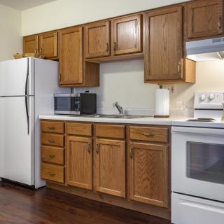 A modern kitchen with wooden cabinets, a refrigerator, stove, and microwave.