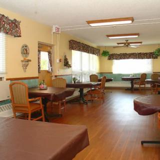 A spacious dining room with neatly arranged tables and chairs, featuring large windows and tasteful decor.