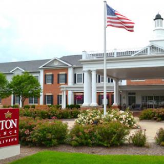 A welcoming view of a hotel with an American flag in front and beautiful landscaping.