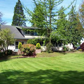 A beautiful residential house surrounded by a lush garden and well-maintained lawn.