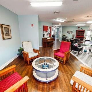 A cozy living room with a seating area featuring armchairs and a round coffee table on wooden flooring.