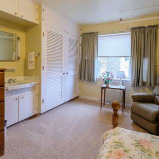 A cozy bedroom with an armchair, window, and floral bedding.