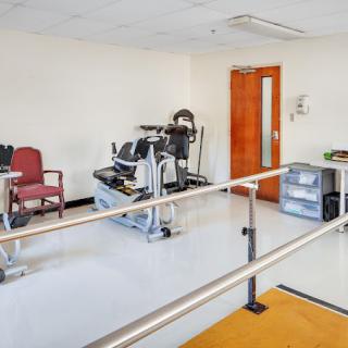A physical therapy room with exercise equipment and parallel bars for rehabilitation exercises.