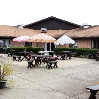 An outdoor patio area with tables, chairs, and colorful umbrellas in front of a building.