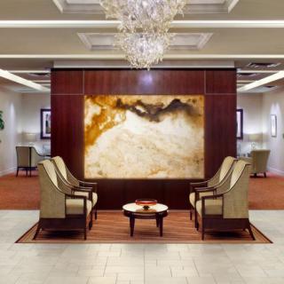 A luxurious lobby featuring elegant seating, a large piece of artwork, and a stunning chandelier.