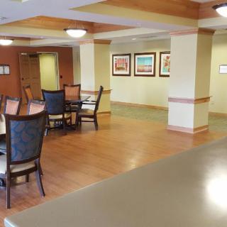 A spacious dining area with chairs and tables, featuring artwork on the walls and wooden flooring.