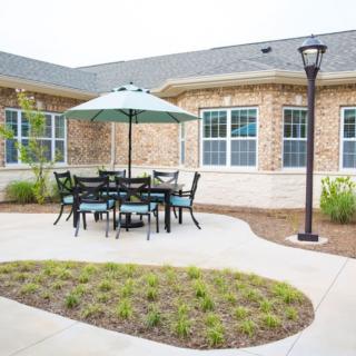 A cozy outdoor patio with a table and chairs under an umbrella in a courtyard setting.