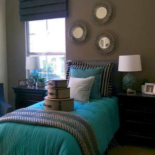 A cozy bedroom featuring a single bed with teal bedding, adorned with decorative pillows and wall art.