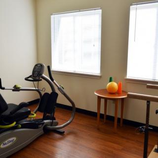 A home gym setup with a stationary bike and a small table decorated with a pumpkin in natural daylight.