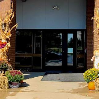 A welcoming entrance adorned with autumn decorations, featuring vibrant flowers and cornstalks.