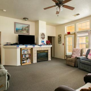 A cozy living room featuring a sofa, fireplace, and television, with natural light streaming through the windows.
