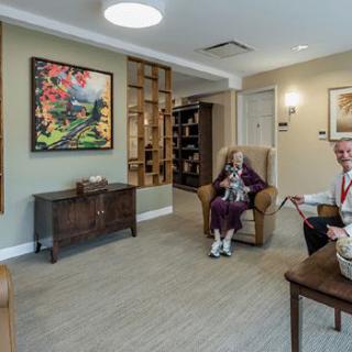 A comfortable common area in a senior living facility, featuring seating and colorful artwork.