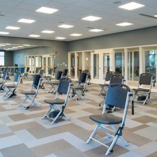 A spacious gym with multiple chairs arranged for a fitness class.