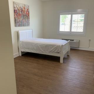 A minimalist bedroom with a single bed and wooden flooring.
