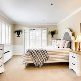 A bright and elegant bedroom with classic decor, featuring a comfortable bed, stylish furniture, and abundant natural light.