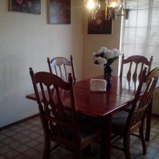 A cozy dining room with a wooden table, chairs, and a chandelier.