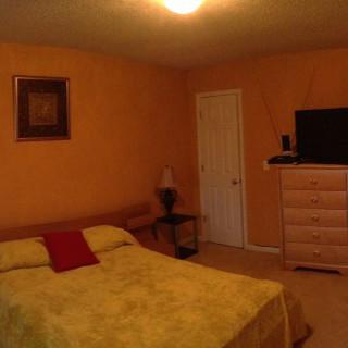 A cozy bedroom with a bed, dresser, and television.