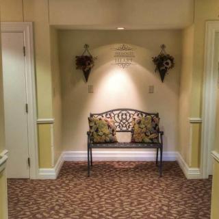 A cozy hallway featuring a decorative bench with floral pillows, flanked by wall ornaments and soft lighting.