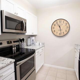 Modern kitchen with stainless steel appliances and a large wall clock.