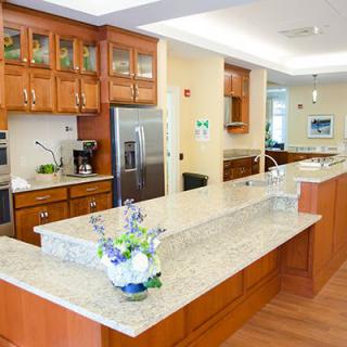 A modern kitchen with wood cabinets, granite countertops, and stainless steel appliances.
