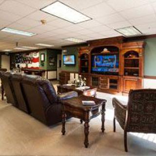 A cozy lounge area with comfortable seating and a large television, surrounded by elegant wooden cabinets.
