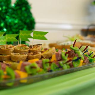 A festive table with a variety of party appetizers and green decorations.