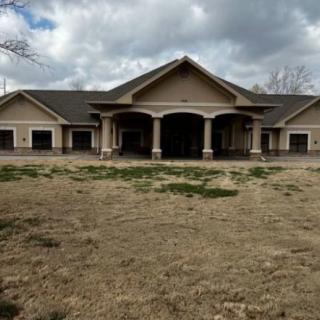 A large suburban house with a covered porch and a cloudy sky overhead.