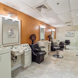 A brightly lit salon interior with multiple styling stations, mirrors, and hair dryers.