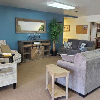 A cozy living room with comfortable sofas, an armchair, and a coffee table set against a blue accent wall.