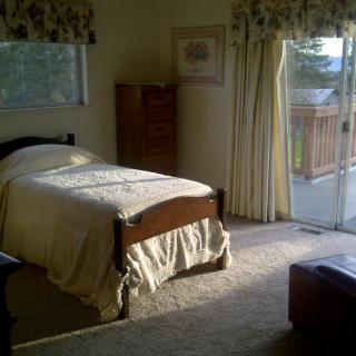A cozy bedroom with a single bed and natural light streaming through the window.